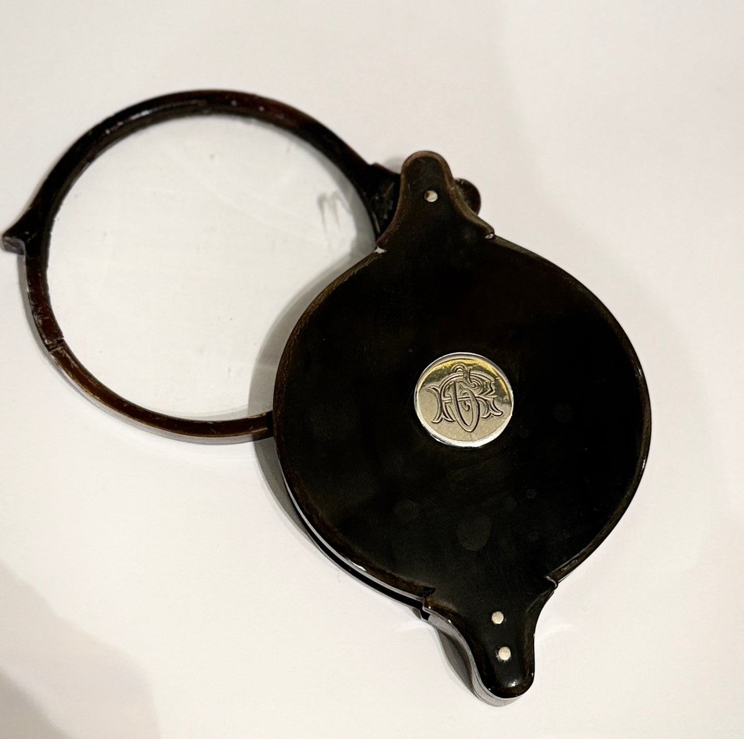 Lupa de bolsillo plegable en cuerno con monograma en plata. Finales s. XIX – pps. s. XX